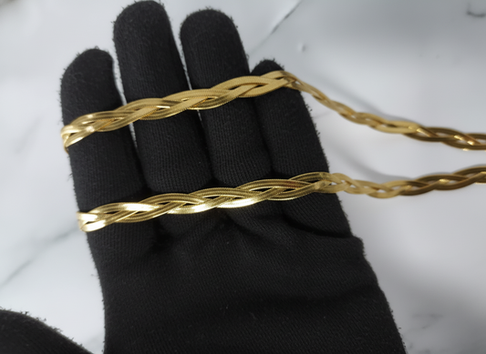Gold bracelet on a black glove against a white background