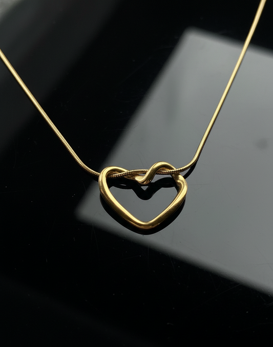Gold heart shaped necklace on a reflective black surface