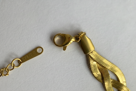 Gold tassel charm with chain on a light gray background