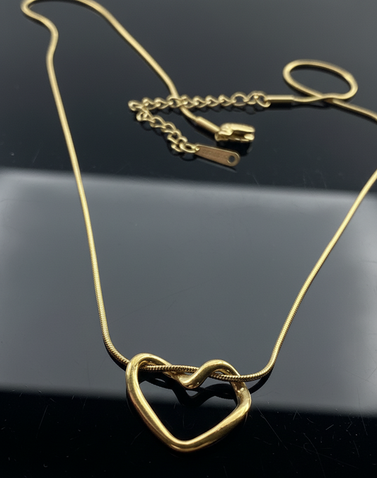 Gold heart-shaped necklace on a reflective black surface