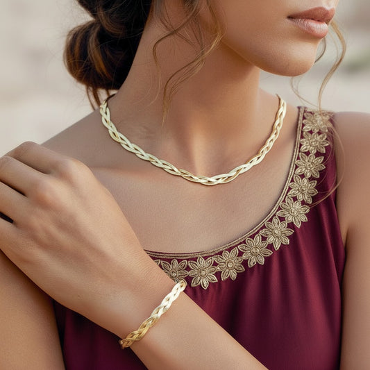 Woman wearing a gold necklace and bracelet with a maroon dress featuring floral embroidery.